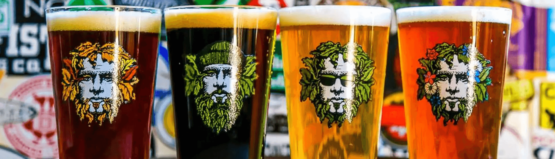 Four pint glasses of craft beer in different colors, each featuring a distinct graphic design of a bearded face with leafy accents.