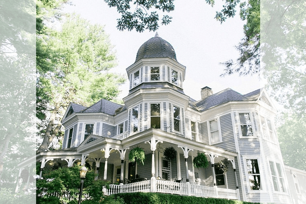 A Victorian-style house with a dome roof surrounded by trees.