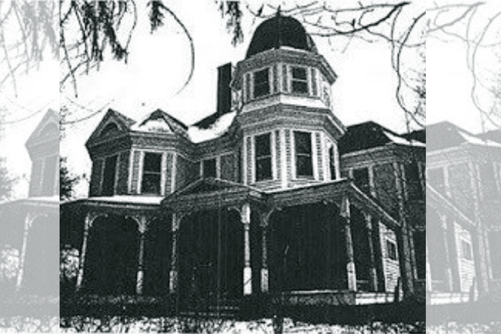 A large, ornate Victorian house with a dome and wrap-around porch, surrounded by trees.
