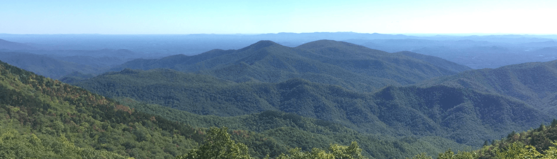 Panoramic view of lush, rolling mountains under a clear blue sky.