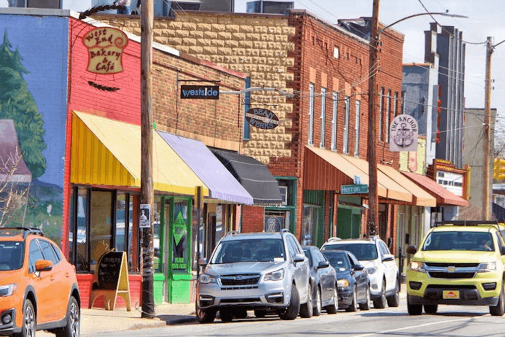 A quaint street lined with colorful storefronts and parked cars.