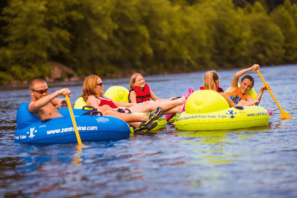 A group of people enjoy tubing on a river surrounded by lush greenery.
