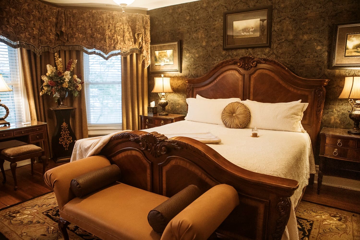 Elegant bedroom featuring a wooden bed, decorative pillows, and rich, textured wallpaper.