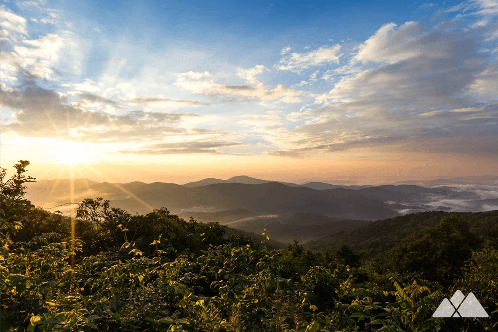Sunrise over misty mountains under a colorful sky.