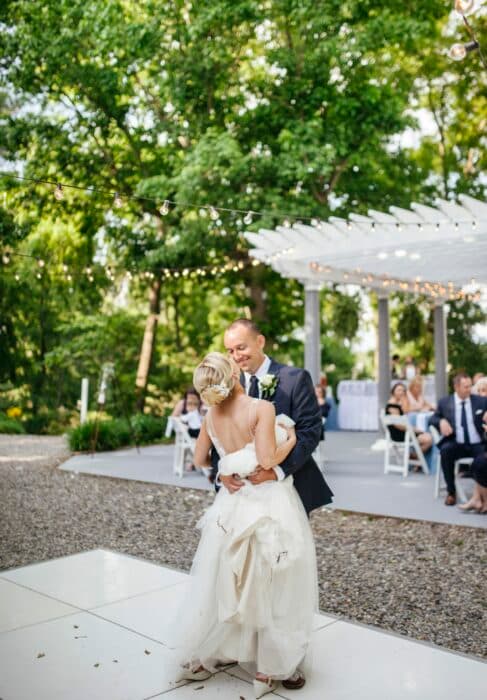 A couple shares a romantic dance at their outdoor wedding reception.