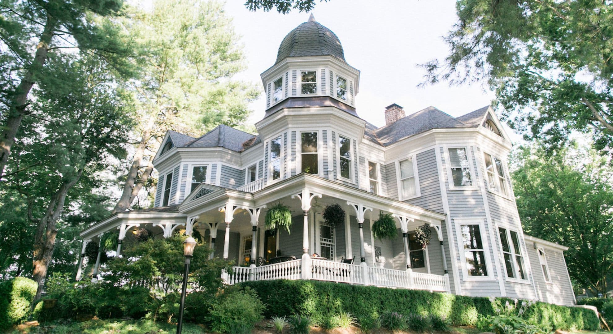 Victorian-style house surrounded by lush greenery.