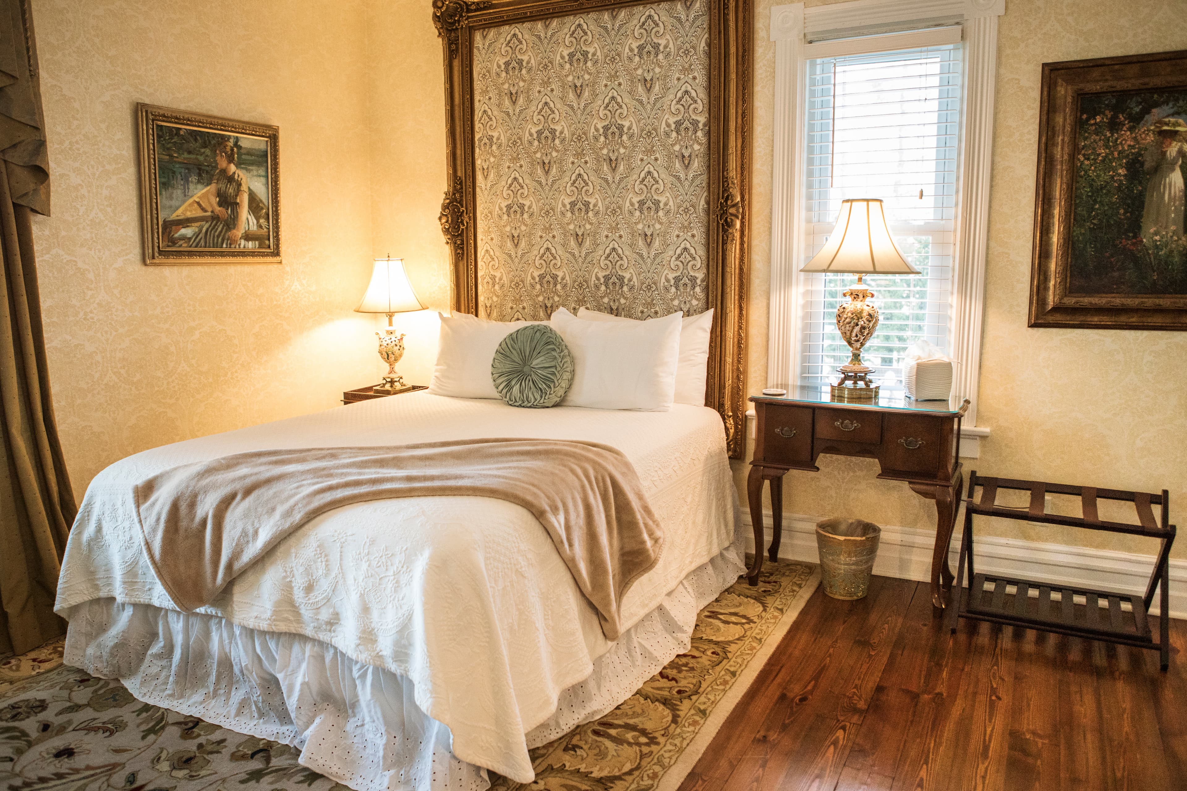 A cozy bedroom with a white bed, decorative pillows, and vintage furnishings.