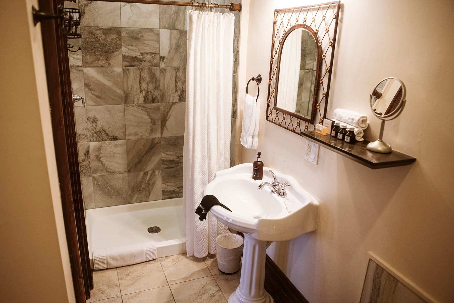 A neatly designed bathroom featuring a shower, sink, and mirror with decorative accents.