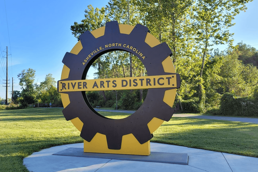 Sign for the River Arts District in Asheville, North Carolina, framed by greenery.