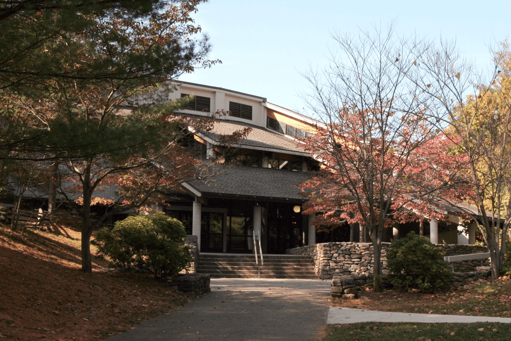 Building entrance surrounded by trees and autumn foliage.