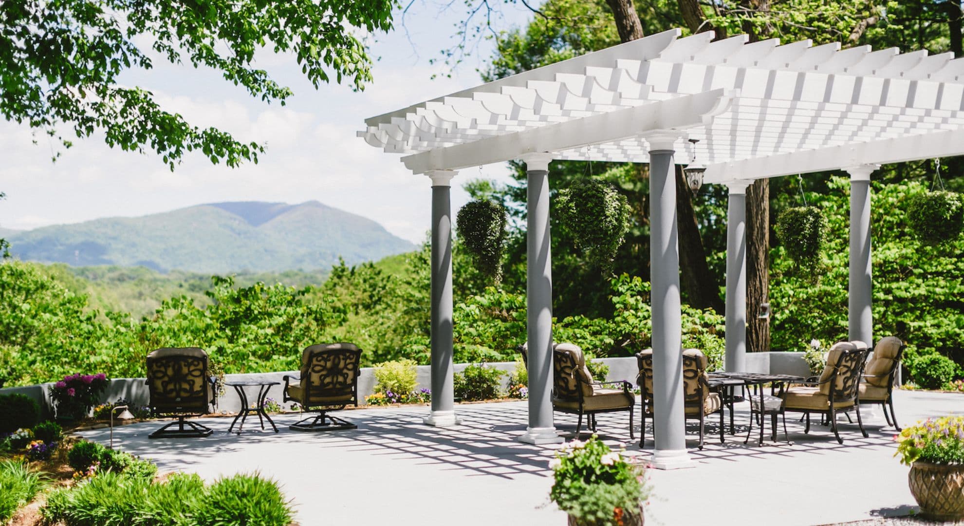 A patio area with comfortable seating and a view of green hills and mountains.