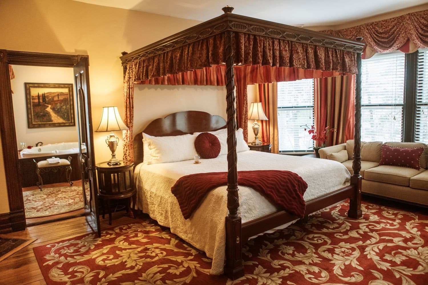 Cozy bedroom featuring a four-poster bed, elegant decor, and a plush seating area.