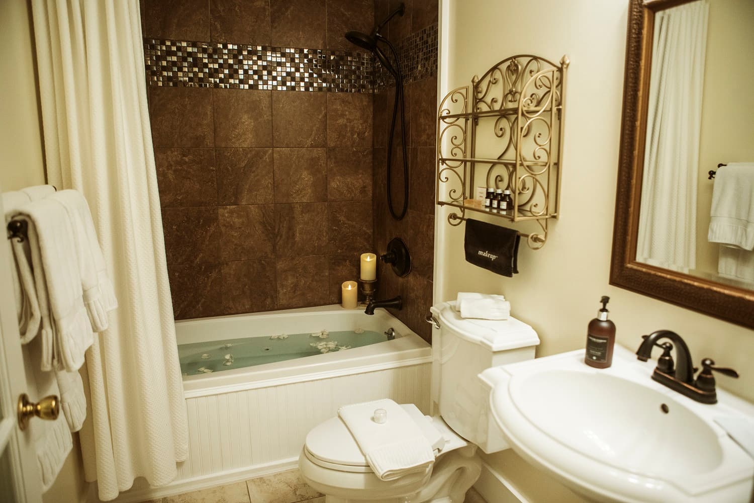 A cozy bathroom featuring a bathtub with candles, a shower, and elegant decor.