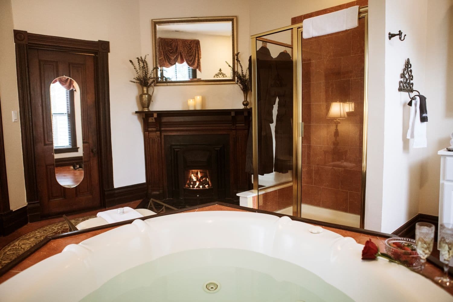 A luxurious bathroom featuring a jetted tub, a fireplace, and a shower, with elegant decor and soft lighting.